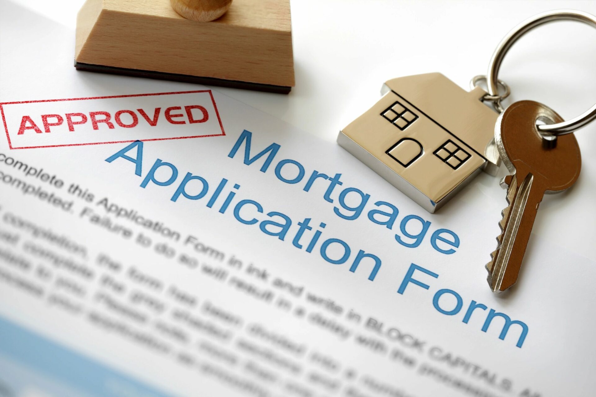 A mortgage application form with a stamp and house key.