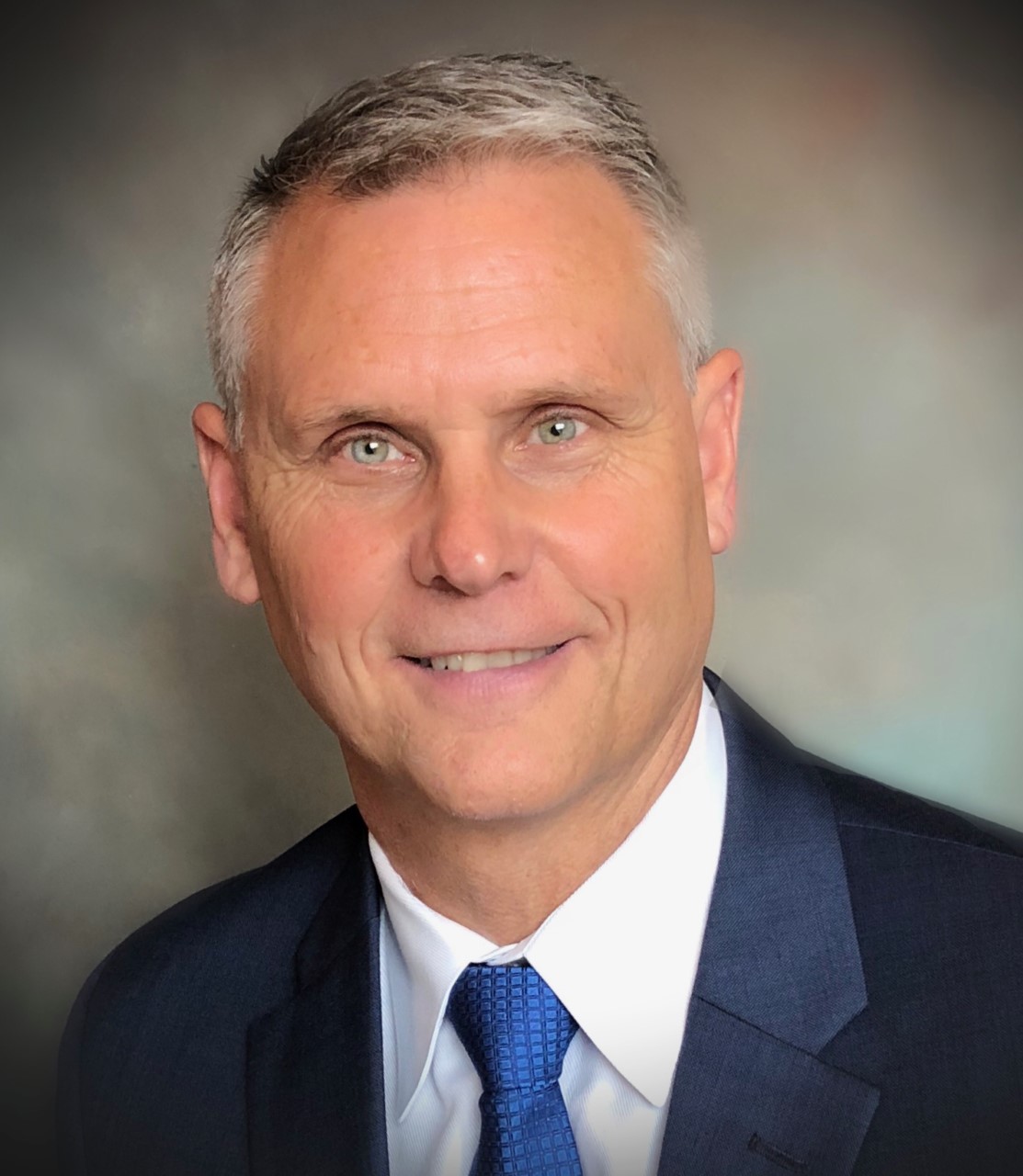 A man in suit and tie smiling for the camera.