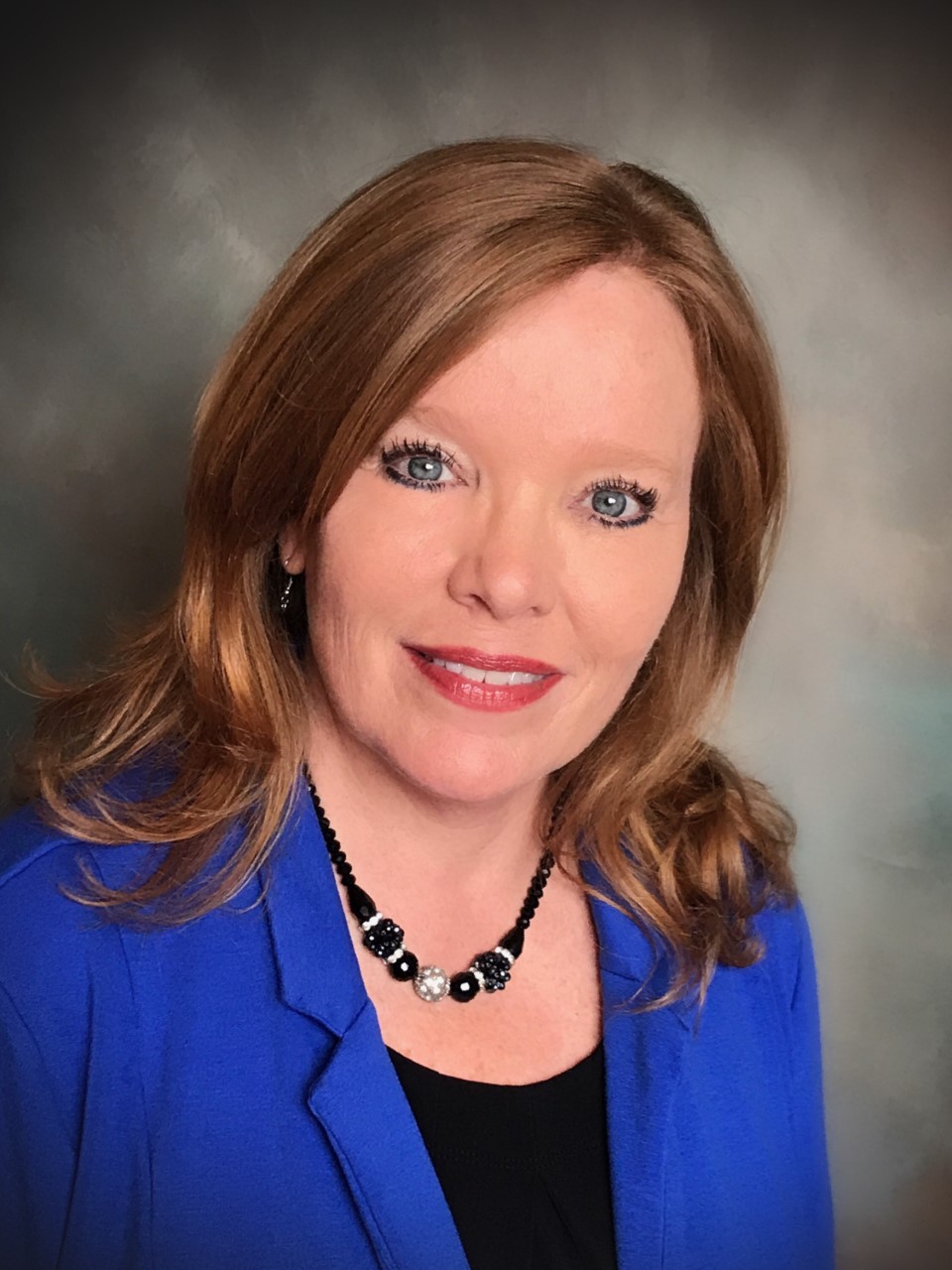 A woman with long hair wearing a blue jacket.