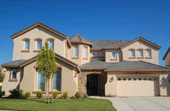 A large beige house with a tree in front of it.